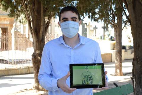 Andrés Martínez, en el cementerio de Los Remedios, mostrando la imagen de la red social Revive.