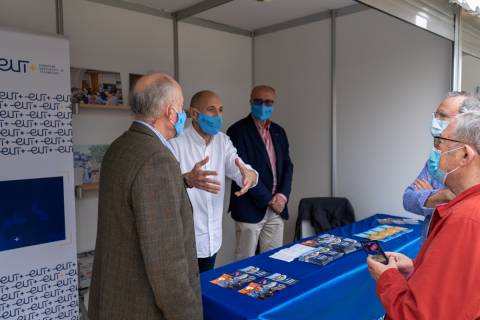 Pedro Luján, coordinador de la Universidad de Mayores, en el centro de la imagen, en el stand de la UPCT.