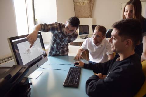 David Lancis, sentado a la derecha, junto a sus compañeros de equipo mirando su diseño de cohete.