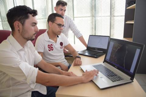 Los tres alumnos fundadores de la asociación revisando una imagen satelital del Mar Menor y una gráfica con la evolución del nivel de clorofila.