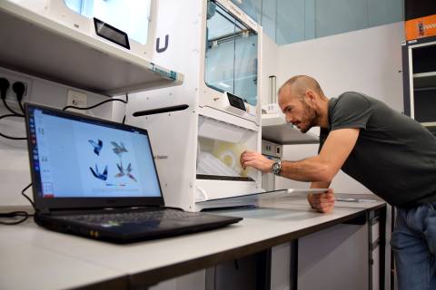 Rogelio Ortigosa comprobando una de las impresoras 3D en las que reproduce diseños computacionales como los que muestra el portátil.