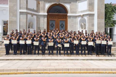 Los 65 graduados posando con sus diplomas.