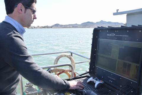El investigador Juan Carlos Molina revisando las imágenes enviadas por el dron Pluto, al fondo en el mar.