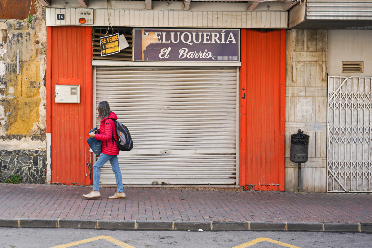 Una viandante pasando por delante de un negocio quebrado en Cartagena.